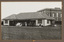Black and white photograph of a men, some in sporting clothes, posing in front of a sporting club house