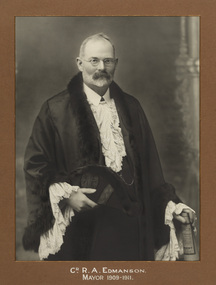 Black and white photograph a formal portrait of standing man with glasses wearing mayoral robes with fur trims and lace cuffs and jabot.