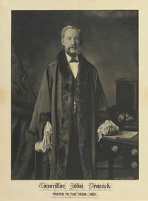 Gelatin silver photograph of a formal portrait of standing man wearing mayoral robes with fur trims and lace cuffs.