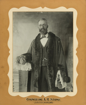 Black and white photograph of a formal portrait of a bearded man wearing mayoral robes with fur trims and lace cuffs with a three piece suit underneath