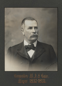 Black and white photograph of a formal portrait of a man, chest up in a dark suit.