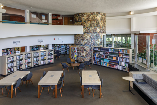Photograph of a library in a round room, in the distance is a ceramic mural