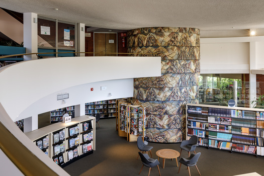 Photograph of a library in a round room, in the distance is a ceramic mural