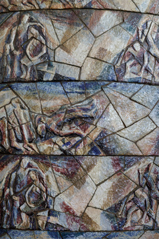 Photograph of a close up of a ceramic mural with depictions of abstracted figures