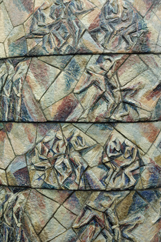 Photograph of a close up of a ceramic mural with depictions of abstracted figures