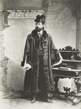 Black and white photograph of a formal portrait of standing man wearing mayoral robes with fur trims and lace cuffs with shirt, waistcoat and tie underneath.
