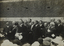 Black and white photograph of a group of suited men addressing a crowd