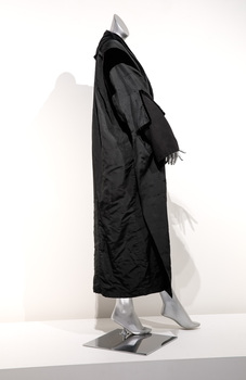 Photograph taken on the side of a black full length ceremonial robe on a silver mannequin. 