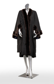 Photograph of a black ceremonial robe with fur trim on a silver mannequin.