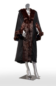 Photograph of a black ceremonial robe with brown fur trim on a silver mannequin.