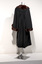 Photograph taken from the back of a black ceremonial robe with brown fur trim on a silver mannequin.