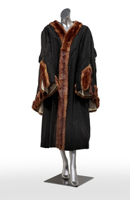 Photograph of a black ceremonial mayoral robe with brown fur trim on a silver mannequin.