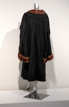 Photograph taken from the back of a black ceremonial mayoral robe with brown fur trim on a silver mannequin.