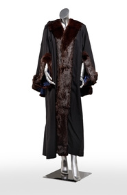 Photograph of full length black ceremonial mayoral robe with dark fur trim on a silver mannequin.