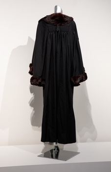 Photograph taken from the back of full length black ceremonial mayoral robe with dark fur trim on a silver mannequin.