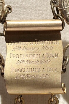 Detail photograph of a gold scroll from the City of Brighton Mayoral Chain - the scroll is inscribed with writing about City of Brighton's history