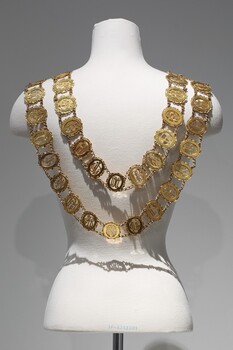 Photograph of the back of a gold ceremonial mayoral chain consisting of small oval links on a mannequin torso.