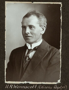 Black and white photograph of a man in a suit with his name written underneath on the mount