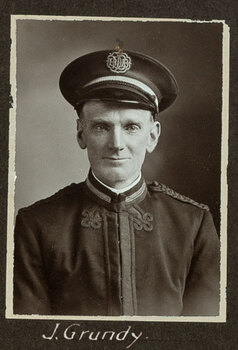 Black and white photograph of a man in a uniform and cap with his name written underneath on the mount