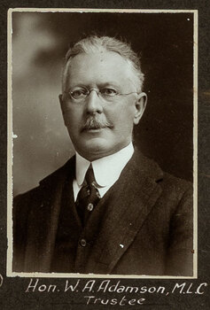 Black and white photograph of a man in a suit with his name written underneath on the mount
