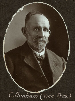 Black and white oval photograph of a man in a suit with his name written underneath on the mount