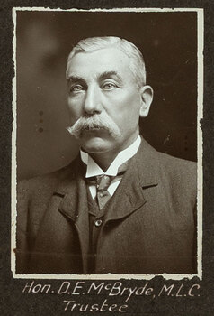 Black and white photograph of a man in a suit with his name written underneath on the mount