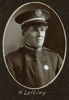 Black and white oval photograph of a man in a uniform and cap with his name written underneath on the mount