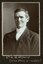 Black and white photograph of a man in a suit with his name written underneath on the mount