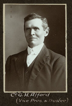 Black and white photograph of a man in a suit with his name written underneath on the mount
