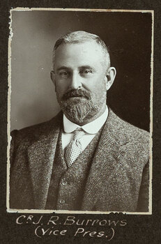 Black and white photograph of a man in a suit with his name written underneath on the mount