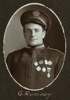 Black and white oval photograph of a man in a uniform and cap with his name written underneath on the mount