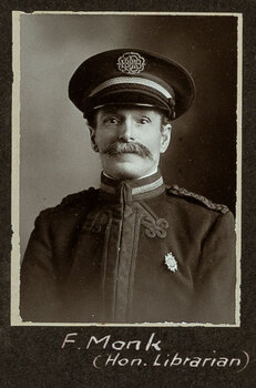 Black and white photograph of a man in a uniform and cap with his name written underneath on the mount