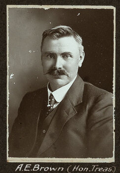 Black and white photograph of a man in a suit with his name written underneath on the mount