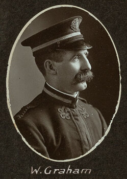 Black and white oval photograph of a profile of a man in a uniform and cap with his name written underneath on the mount
