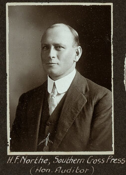 Black and white photograph of a man in a suit with his name written underneath on the mount