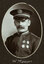 Black and white oval photograph of a man in a uniform and cap with his name written underneath on the mount