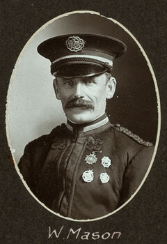 Black and white oval photograph of a man in a uniform and cap with his name written underneath on the mount