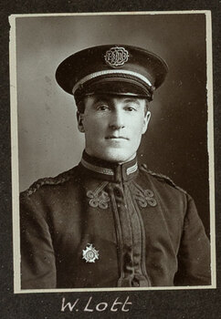 Black and white photograph of a man in a uniform and cap with his name written underneath on the mount