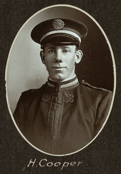 Black and white oval photograph of a man in a uniform and cap with his name written underneath on the mount