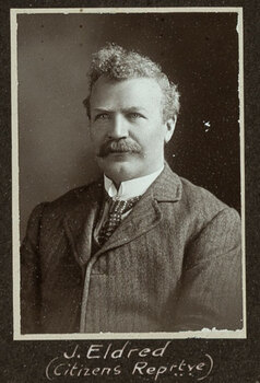 Black and white photograph of a man in a suit with his name written underneath on the mount