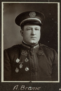 Black and white photograph of a man in a uniform and cap with his name written underneath on the mount