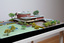 Architectural model of a cylindrical building in orange brick surrounded by gardens and paths