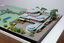 Architectural model of a cylindrical building in orange brick surrounded by gardens and paths