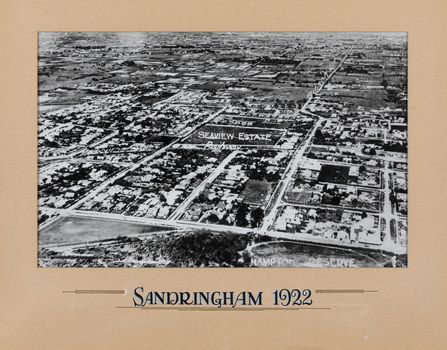 Black and white aerial photograph of Sandringham with Hampton Reserve lower right and Seaview Estate in the centre. Photograph surrounded by cream mount with handwritten lettering 'SANDRINGHAM 1922' below