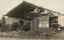 Sepia photograph of a factory building damaged by a cyclone, missing walls and a roof, building debris all around it