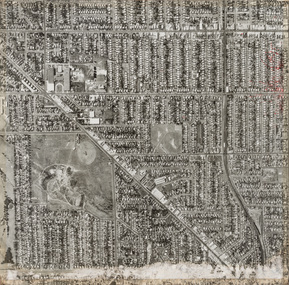 Black and white aerial photograph of streets lined with buildings, a large park is situated lower left.
