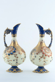 Pair of ceramic urns with handles, pouring spout and base decorated in blue and gold. Main body decorated with floral motifs and gold colour.