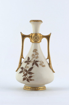 Cream coloured ceramic vase with two gold glazed handles and top and bottom rims gilded. Floral decoration in brown colour on body of vase.