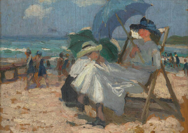 Seated woman under a blue umbrella at the beach in foreground with figures in the distance on the sand and in the water.