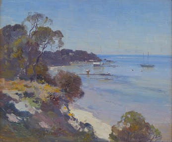 Beachscape with rocks and trees in foreground and still water, piers, trees, buildings and sailing boat in the background.